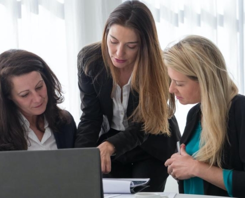 Three women looking at a laptop to discuss content marketing