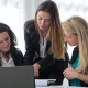 Three women looking at a laptop to discuss content marketing